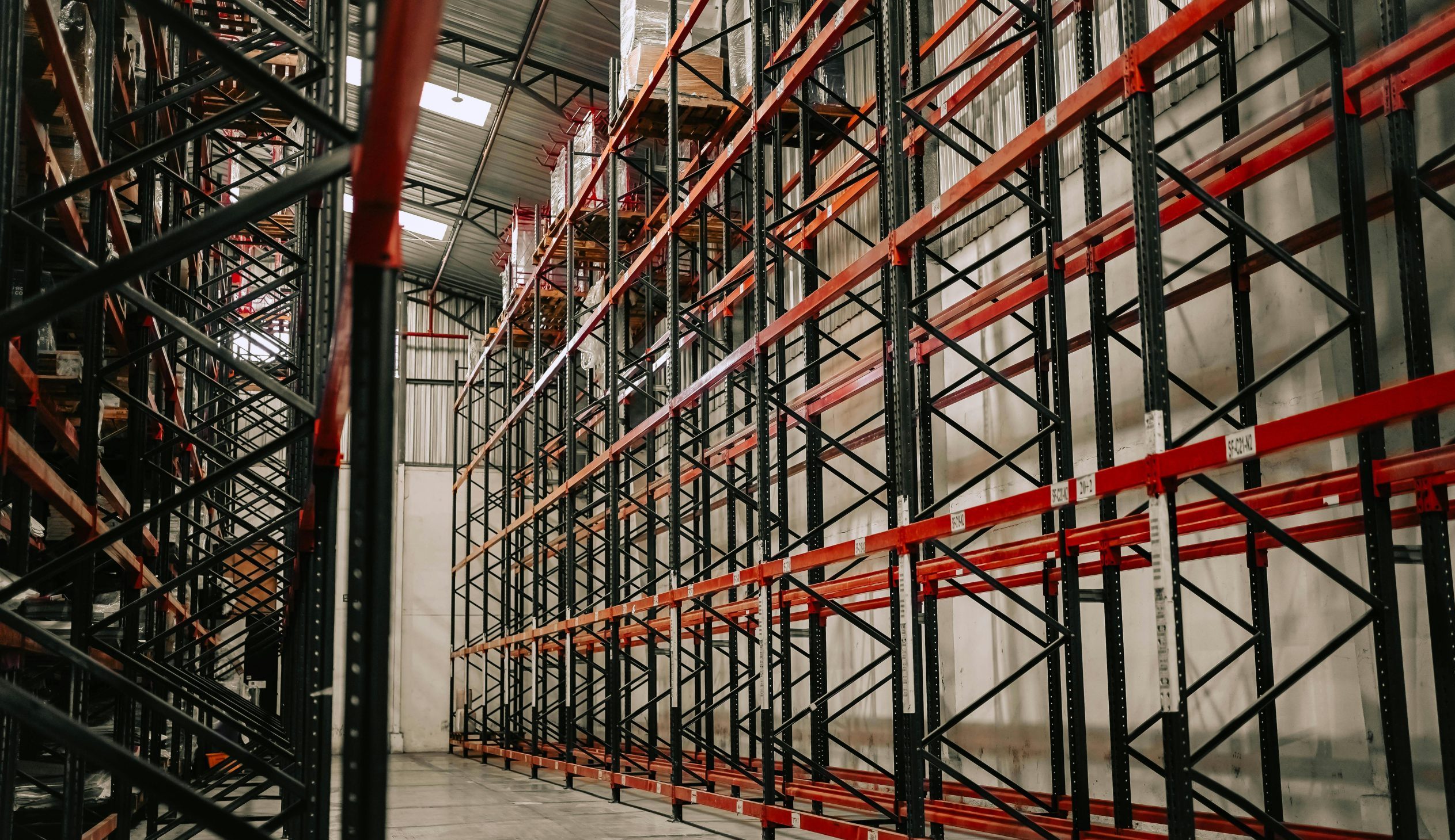 Spacious warehouse interior featuring empty metal racks and high ceiling.