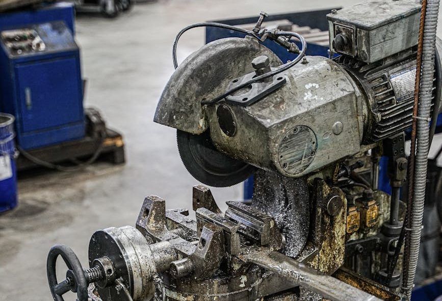 Vertical shot of industrial machine cutting pipes in a factory.