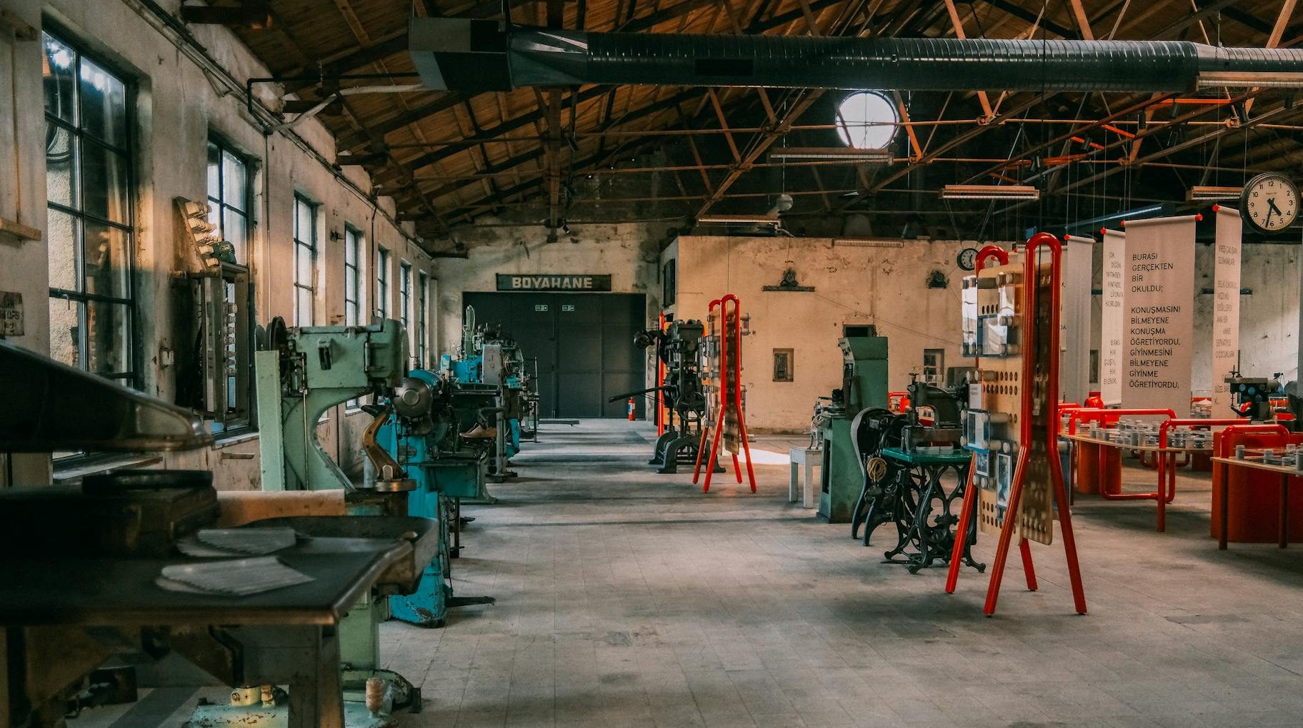 An expansive industrial workshop featuring vintage machinery and tools under a wooden roof.